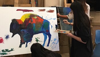 Native American student working on a colorful buffalo painting